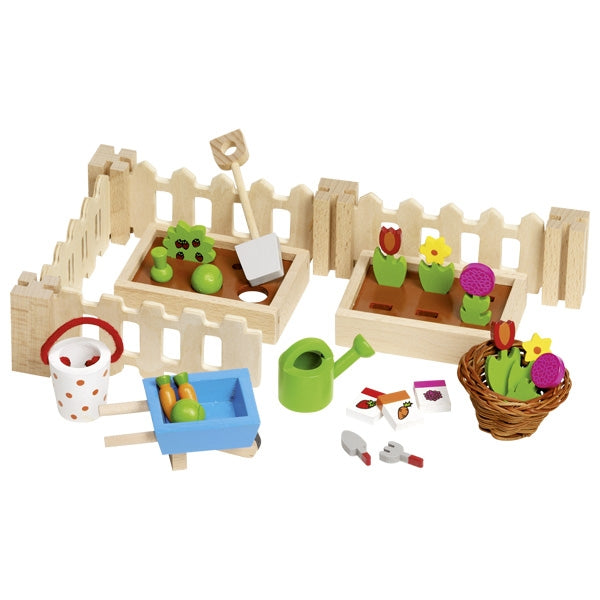 Children's toy garden set with wooden fence, plants, and gardening tools on a white background